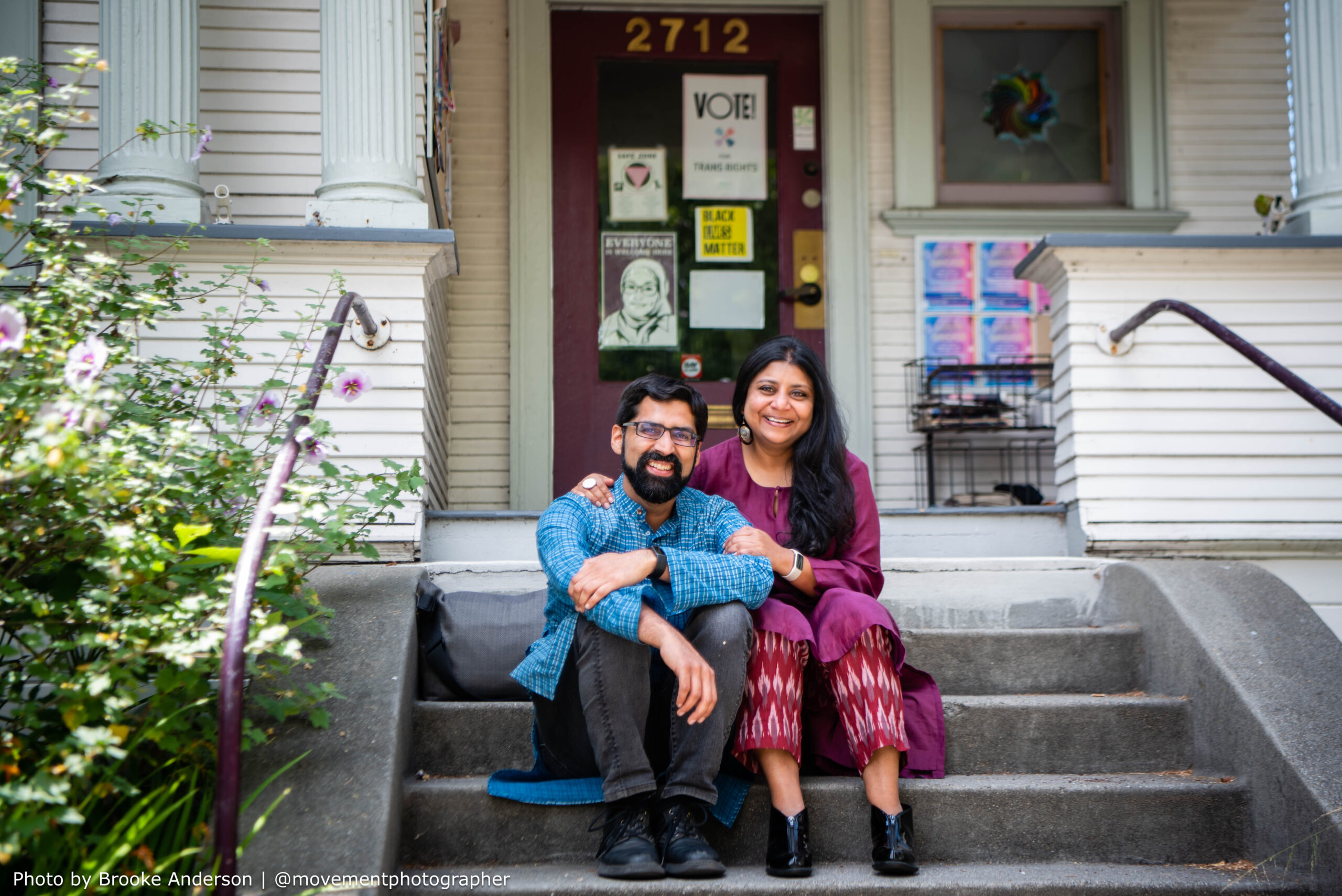 Barnali and partner seated in front of a building